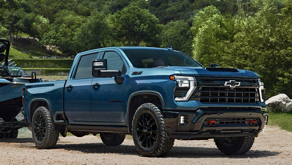A blue 2026 Chevrolet Silverado HD truck towing a boat