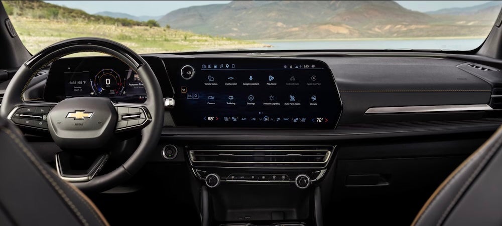 The steering wheel and dashboard of the 2027 Chevrolet Traverse SUV, with mountains in the distance